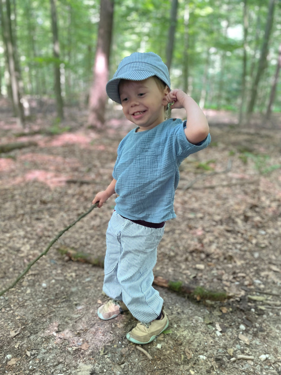 Miniaturbild: Ein lächelnder Junge in blauer Kleidung hält einen Stock, im Wald. Pumphose aus Jeans /Fuchs.