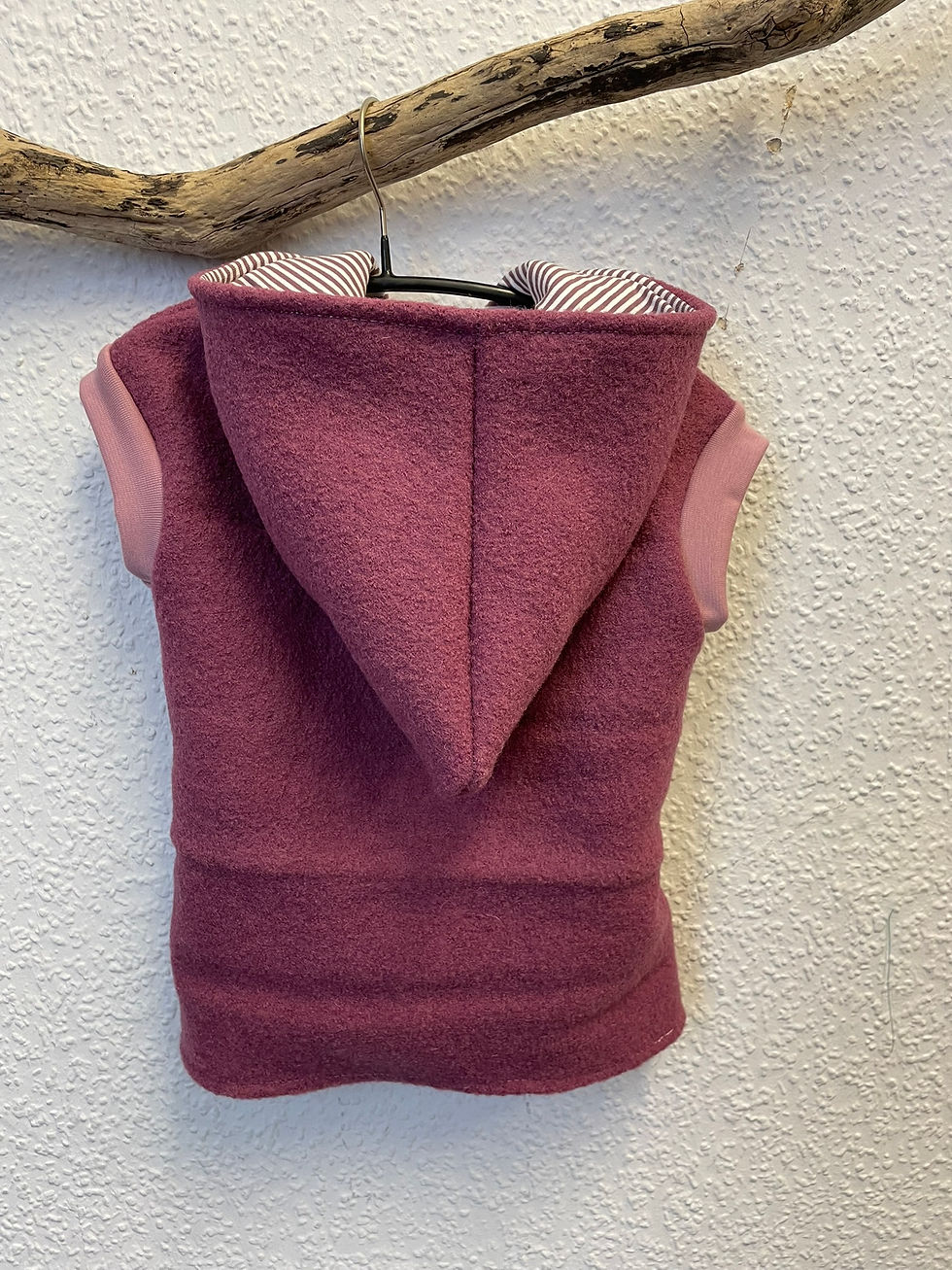 Miniaturbild: Burgunderrote ärmellose Kapuzenjacke an einem Kleiderbügel vor einer Wand