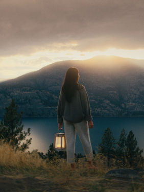 Lady stood with her back to camera looking out over lake at sunset.