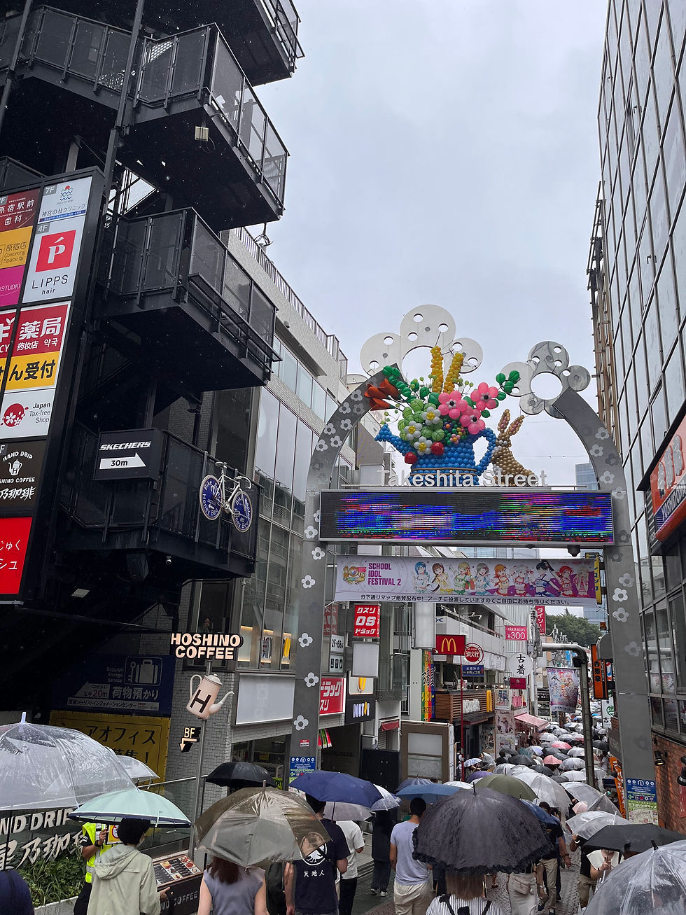 A rainy day on Takeshita Street in Tokyo, bustling with people under colorful umbrellas.
