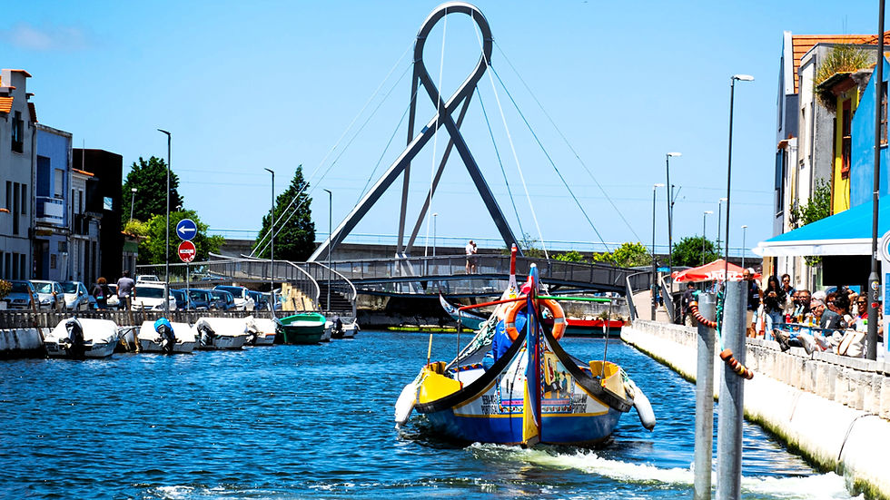 Traditional Moliceiro boat sailing through the canals of Aveiro, Portugal, with the modern bridge and waterfront in the background.