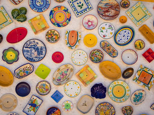Colorful handcrafted ceramic plates with intricate patterns arranged on a white wall background. Vibrant designs evoke a cheerful mood.