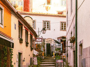 Narrow historic street in Lisbon with colourful buildings, stone steps, and small local restaurants