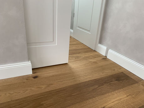 Heller Dielenbereich mit Holzboden und weißer Tür als Fensterbankbereich