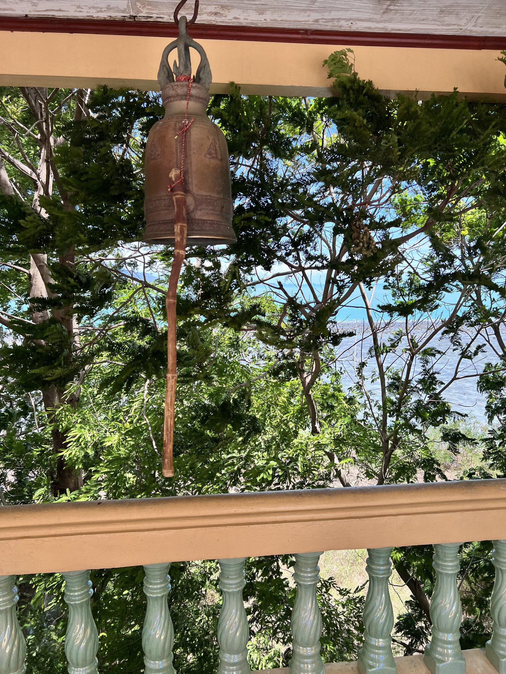 Original travel photograph: an old bell hanging before a sunlit canopy