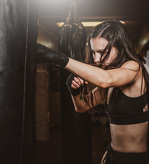 skinny-focused-woman-has-boxing-training-with-punching-bag-dark-gym.jpg