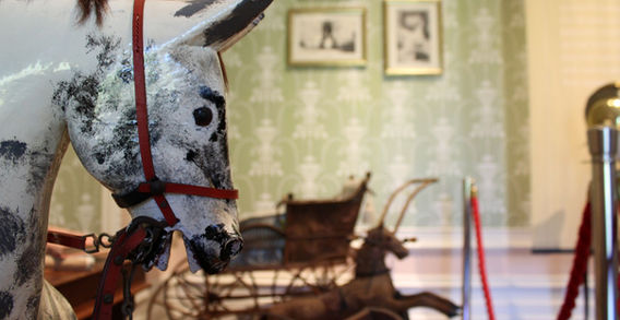 Gros plan sur la tête d'un ancien cheval de bois à taches noires avec une bride rouge, exposé dans une pièce historique à l'abbaye de Kylemore.