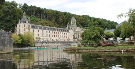 L'abbaye de Brantôme et son clocher roman vus depuis la rivière Dronne avec des canoës sur l'eau.