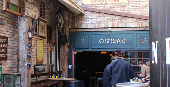 Photographie de la cour intérieure (beer garden) du pub The Bleeding Horse à Dublin, architecture historique en briques et bois, enseigne vintage Player's Navy Cut et zone O'Shea's, voyage authentique Lawscape.