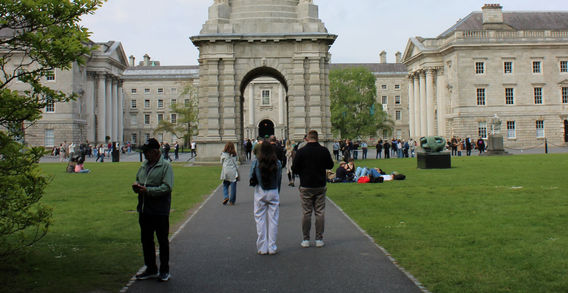 Allée centrale menant au Campanile de Trinity College à Dublin, entourée de pelouses verdoyantes.