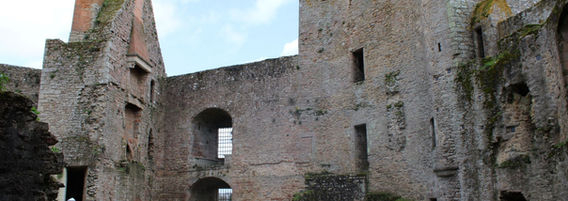 Vue d'angle sur les hauts murs de pierre du château de Clisson entourant une cour intérieure, sous un ciel clair.