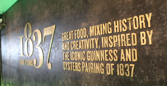 Inscription murale dorée expliquant l'accord historique entre la Guinness et les huîtres datant de 1837.