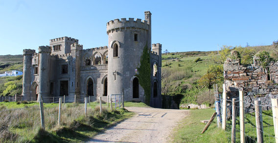 Vue en gros plan des ruines en pierre de Clifden Castle avec tours et chemin d'accès en terre en Irlande.