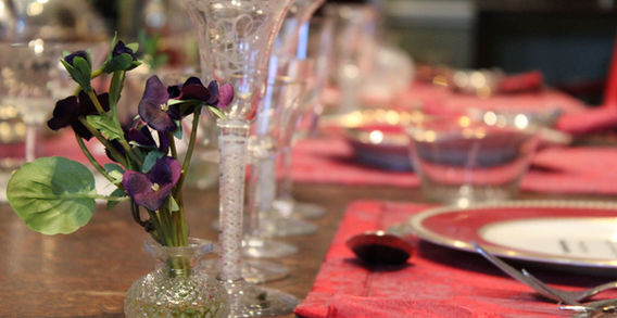 Gros plan sur un petit vase en cristal contenant des fleurs violettes, posé sur une table de salle à manger dressée à l'abbaye de Kylemore.