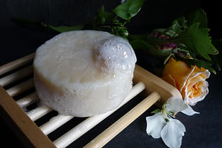 bamboo slatted Draining soap dish with a bar of soap on top that has soap bubbles on it.