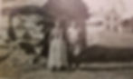 This couple pictured may be I-kwe-wish’s parents: An-ji-gi-ji-go-kwe and Wap-i-ges.  Thad Thayer’s white house is in the background behind this log cabin.  (circa 1893) 