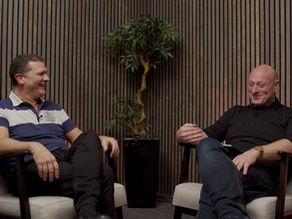 Two men laughing in a podcast studio