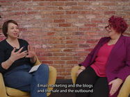 Two women talk in a studio on a podcast