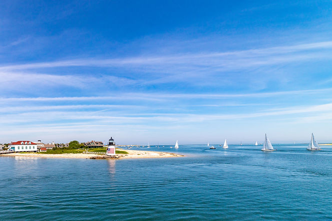 Lighthouse and sailboats under a blue sky day in the Nantucket Harbor..jpg