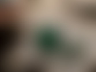 Emerald-cut green gemstone on a weathered wooden surface, with scattered gem chips beside it, in a moody close-up.