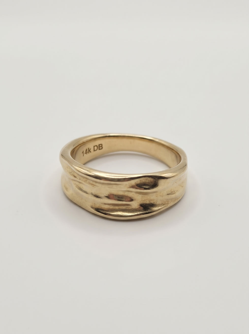 Alternate view of the gold ring showing its sculptural contours and dimensional surface.