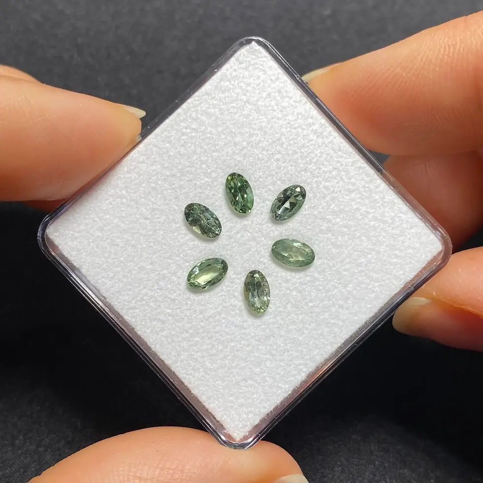 Close-up of the six calibrated Songea sapphires showing sage and olive-green tones.