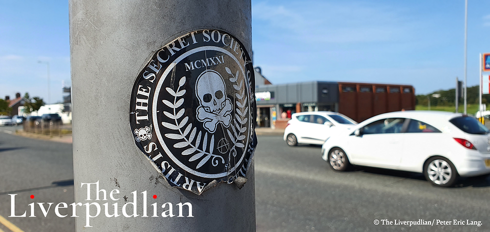 A 'Secret Society of Super Villain Artists' sticker on a lamp post at the junction outside of the Prenton YMCA charity shop (Credit: The Liverpudlian/Peter Eric Lang).