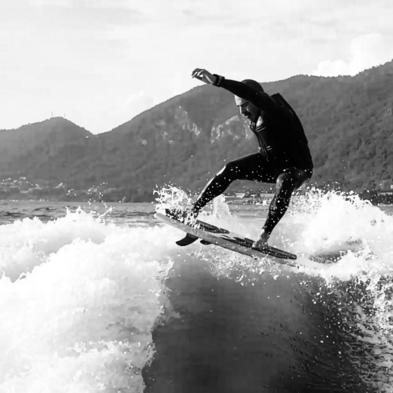 Un uomo in surf sull'acqua con le montagne sullo sfondo