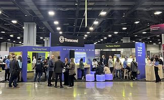 Corporate event expo booth with attendees, screens, seating, speakers, signage, and live product demonstrations