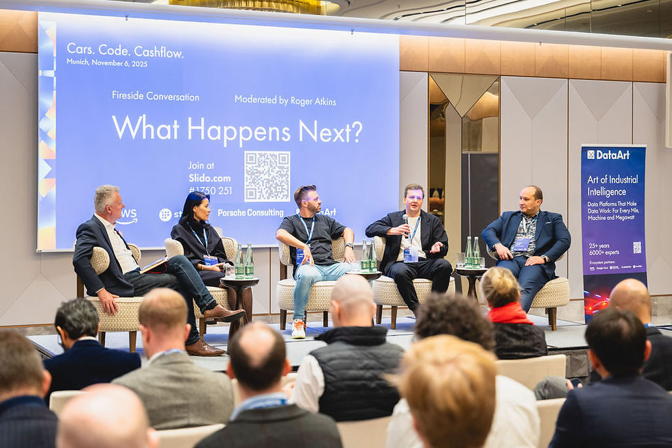 Panelists seated on stage discussing "What Happens Next?" at Cars. Code. Cashflow. event. Audience watching in a modern room.