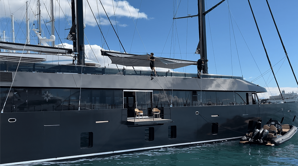 REPOSADO's crew adjusts a sunshade on a sleek. An inflatable boat is docked beside it.