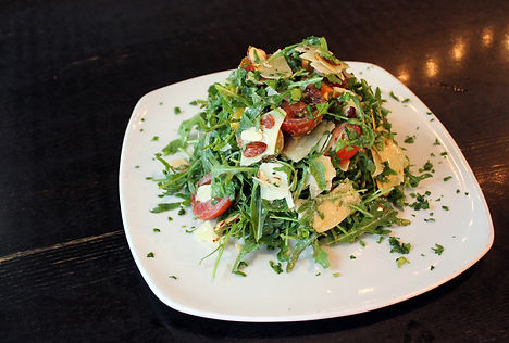 Bacon Wedge. Arugula tossed in house made lemon vinaigrette, shaved Parmesan, baby heirloom tomatoes, and toasted almonds.