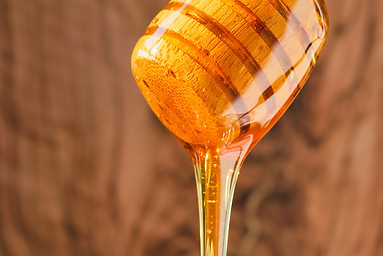 honey-flows-from-wooden-honey-stick-into-jar-vertical-shot-closeup-selective-focus-honey-n