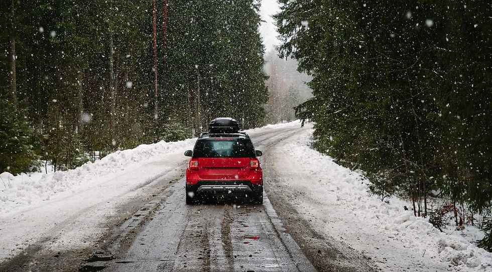 Red car driving smoothly on a snowy road, showcasing proper winter car maintenance for safe driving in cold conditions.