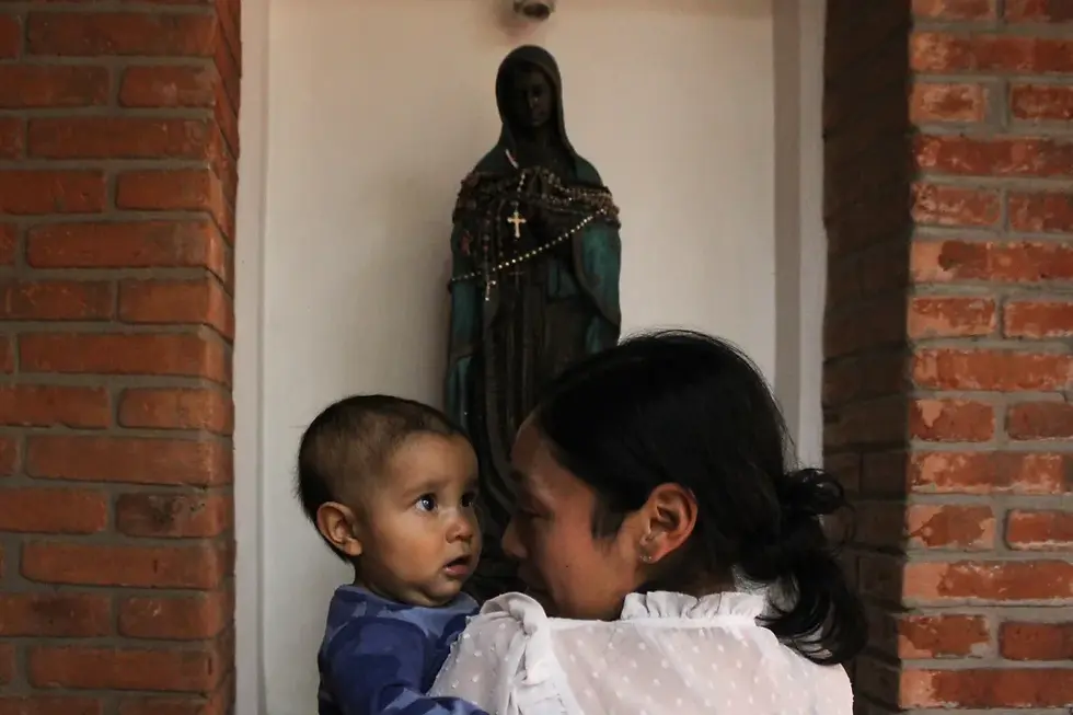 Abrazando a Juanito frente a una estatua de la virgen María en el centro AMANC, Luisa estudia los ojos de su hijo (Imagen: Mark Viales / Al Jazeera).