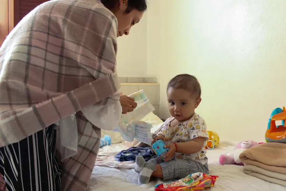 Sentado en su cama del refugio AMANC, Juanito espera a que su madre cambie su pañal (Mark Viales / Al Jazeera).