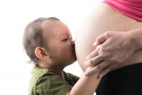 Toddler kissing his pregnant mom's belly