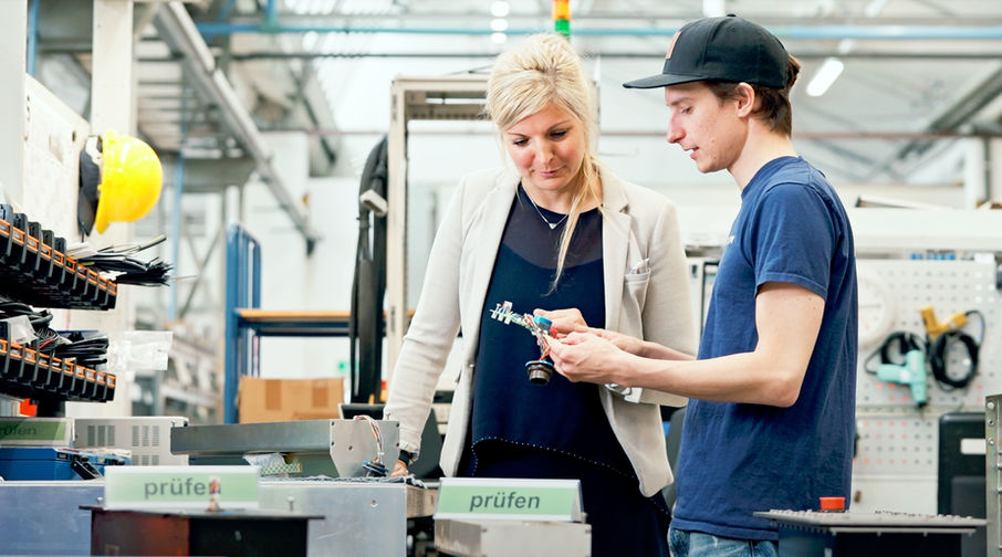 Projektmanagerin im Bereich Service Obsolesence Management spricht mit Mitarbeiter