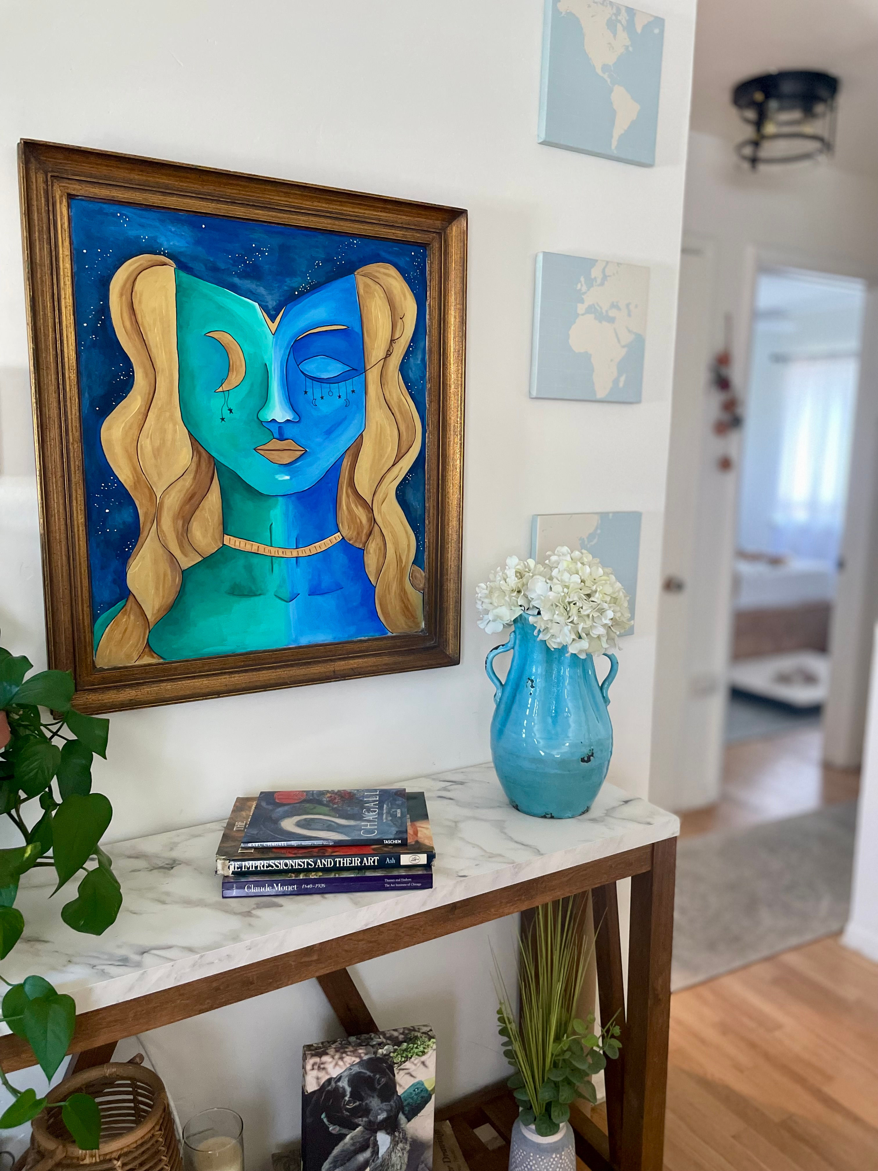 View of the original painting of the Beautifully Balanced goddess displayed over a table in a living room as home decor. 