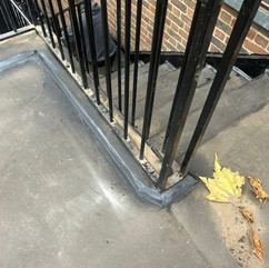 A modern black stair railing accompanied by a bold red bag