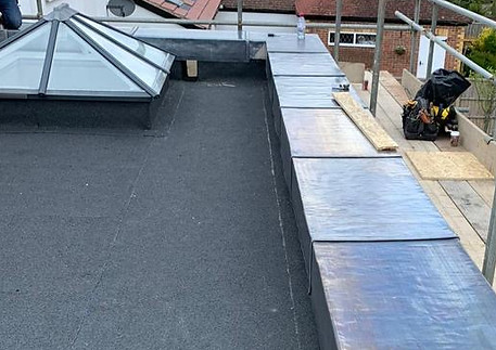  Flat roof with a skylight and cover, showcasing recent repairs for improved functionality and aesthetics.