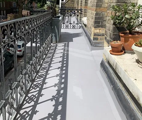 A balcony with a metal railing and potted plants, featuring waterproof flooring.