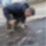 A man is on the roof, cleaning and inspecting the garage roof for signs of damage.