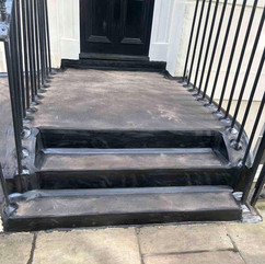 Mastic asphalt stairs with black railings and door entrance.