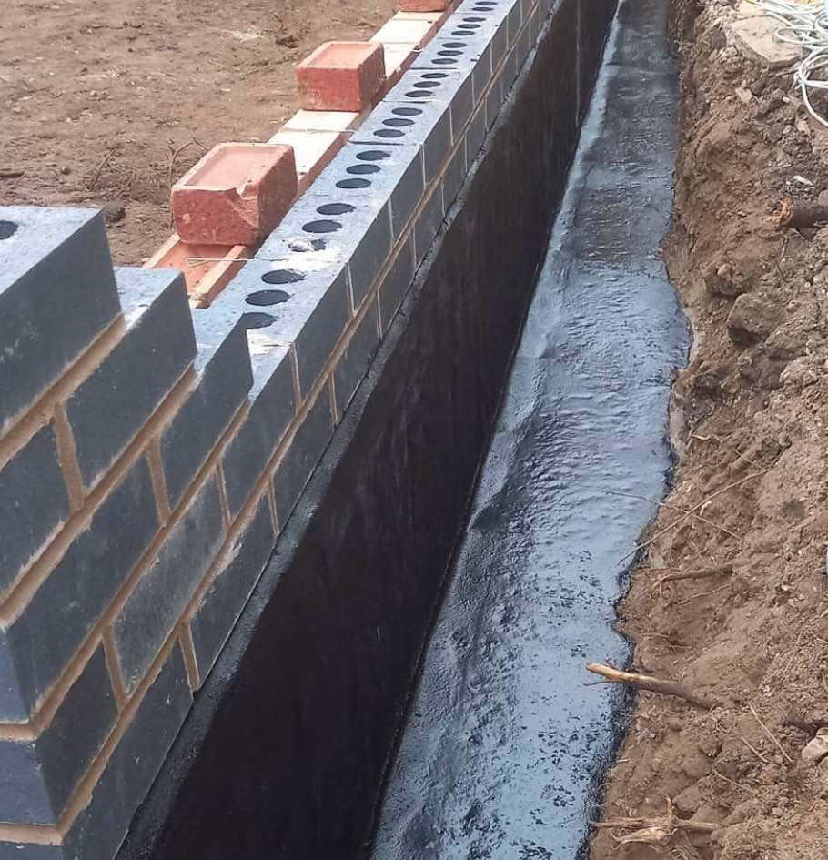 Mastic asphalt applied to a brick wall foundation for waterproofing.