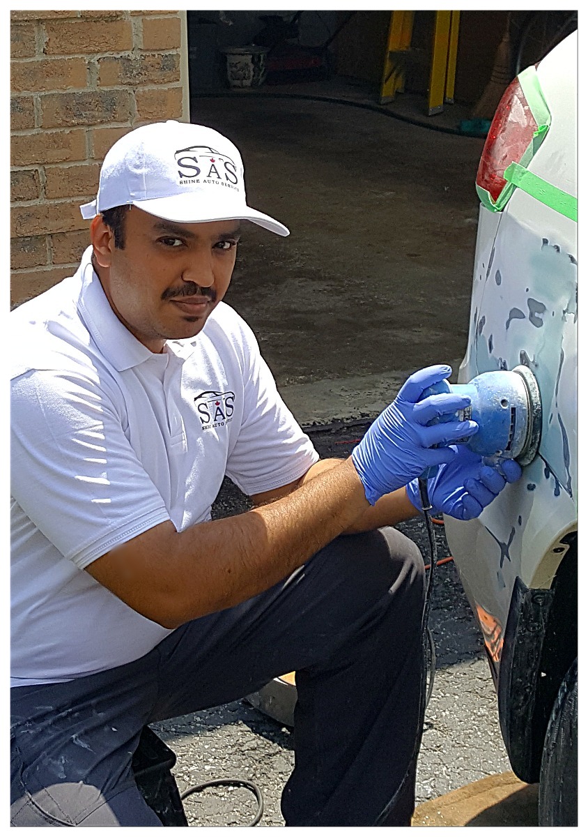 Shine Auto Service technician working on a masked vehicle body panel