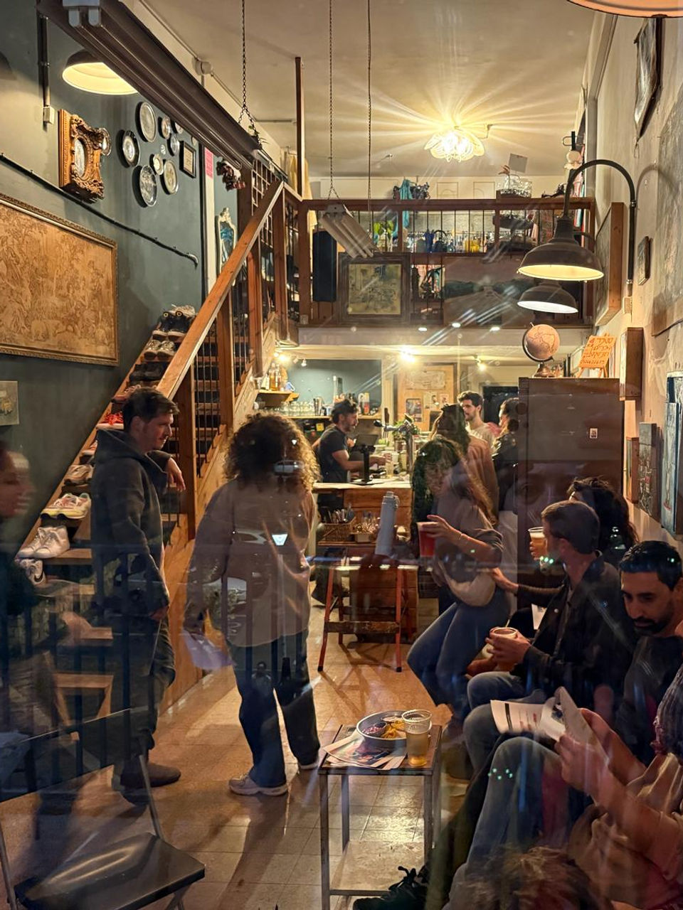אנשים יושבים ועומדים בחלל מעוצב עם תמונות על הקירות וגרם מדרגות