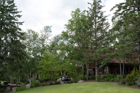 Outdoor patio at Antlers Kitchen + Wine Bar overlooking the golf course with trees, tables, and water features nearby.