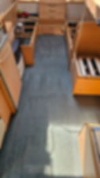 Grey carpet in a narrow caravan walkway with wooden cabinets