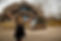 Woman standing with arms in the air in front of a Thatch Roof House.